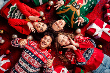 Joyful teenagers celebrating Christmas together surrounded by festive gifts and decorations in cozy holiday sweaters