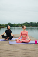 Women Practicing Yoga and Meditation on a Dock by the Lake During a Peaceful Afternoon for Health and Wellness