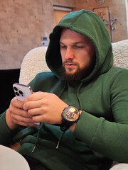 A casual young man using a phone at home or cafe.