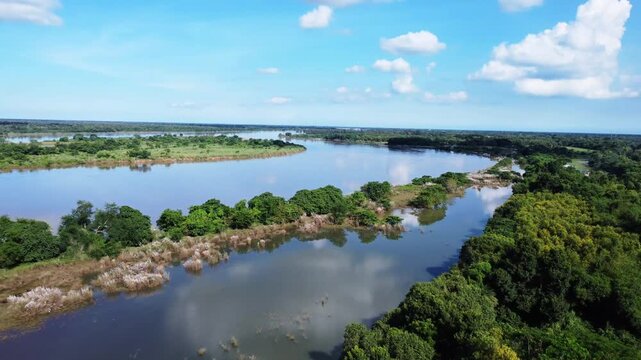 Aerial view of tranquil winding river reflecting sky, amid lush green landscape 4K view. Mahanadi river known as one of the best indian river under blue cloudy sky.