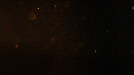 Abstract golden light overlay features dancing bokeh circles and streaking lights against a dark background, perfect for adding atmospheric, glittering texture or holiday charm.