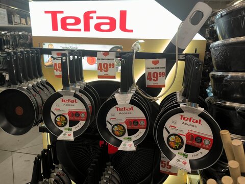 Tefal Access frying pans displayed on a store shelf with visible price tags and red logo, close-up retail product presentation in a supermarket, concept of kitchenware retail, consumer goods
