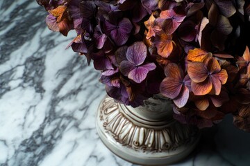 A moody composition of dried purple and burnt orange flowers, likely hydrangeas, arranged in an ornate ceramic vase on a luxurious marble surface, evoking autumnal elegance.