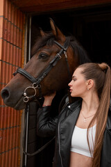 Young woman hugging her horse in stables before a ride