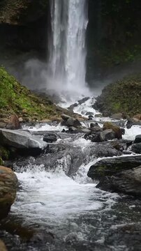 Cascada El Rocio Machay waterfall near Banos de Agua Santa in Ecuador. Flowing water cascades down rocky terrain, creating a serene atmosphere with lush greenery surrounding the waterfall