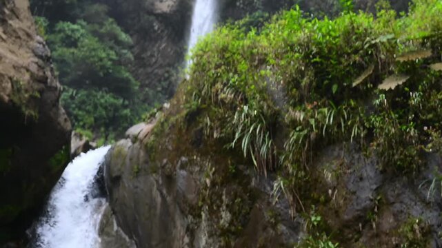 Cascada El Rocio Machay waterfall near Banos de Agua Santa in Ecuador. Majestic waterfall cascades down rocky cliff, creating a serene pool surrounded by lush greenery and smooth stones