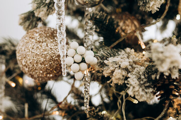 Decorative ornaments on a Christmas tree with snow like embellishments and warm lights