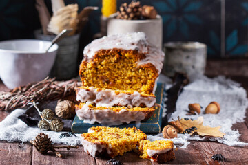 Pumpkin raisin bread with icing, served with tea on a dark background.
