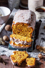 Pumpkin raisin bread with icing, served with tea on a dark background.