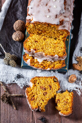 Pumpkin raisin bread with icing, served with tea on a dark background.