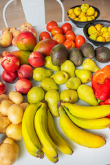 Artistic arrangement of natural foods with   bananas, water pears, Hass avocados, new potatoes, yellow-fleshed nectarines, and black figs on a pastel blue surface
