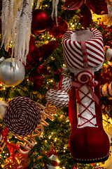 Christmas tree with sparkling garland lights and decorative red Santa Claus boot for gifts, selective focus