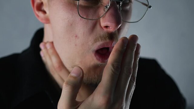 A man in a black shirt and glasses has a sore throat due to strep throat.
Seasonal virus and illness.
Cough and sore throat.
Cough, pandemic, cold, flu, infection