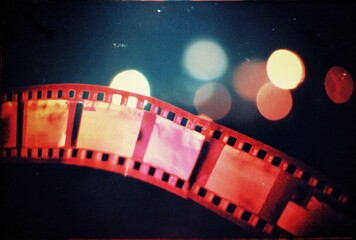 A film strip ribbon dances across a dark scene, with blurred, warm orbs of light in the background