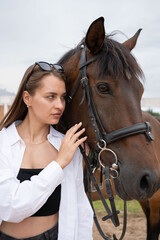 Tender moment between a young woman and a horse in a stable, highlighting a serene and emotional connection.