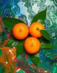Composition of three oranges, fresh leaves on vivid abstract background