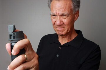 Older Man holding a can of Mace or Pepper Spray for self-protection 