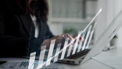 A businesswoman engages in financial data analysis using a laptop while reviewing growth charts in a modern office. Ideal for business and finance projects. Copula - Powered by Adobe