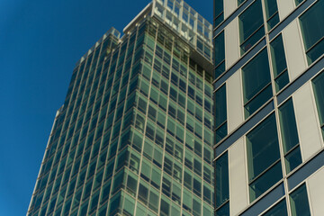 Tall modern office buildings with glass facades taken from low angle, under blue sky. Suitable for...