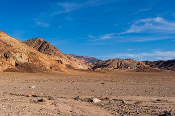 Warm-Toned Sunlit Desert Hills Rising Beyond Rocky Foreground Under Bold Blue Sky
