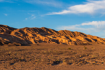 Golden Hour View Near Stovepipe Wells with Reddish-Orange Mountains and Rocky Alluvial Foreground, Death Valley