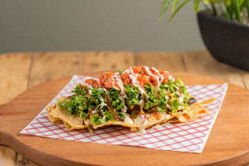 Plate of nachos with lettuce tomato and cheese sauce