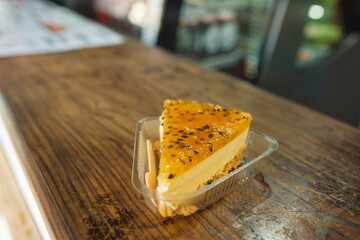 Slice of passion fruit cheesecake on wooden table