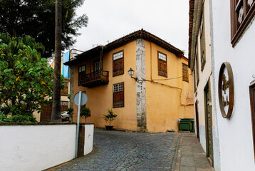 An old yellow house with brown windows and a carved balcony.