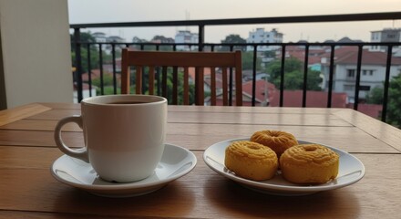 Coffee and donuts on a balcony with a city view.