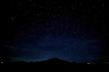 Starry night, silhouetted hill. Glimmering sky. Very dark image