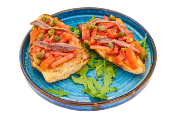Italian bruschetta with fresh tomatoes, capers, anchovies and crusty bread on a blue plate