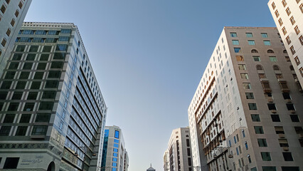 Fototapeta premium An abstract image of a modern glass and concrete building looking upwards. An architectural exterior detail of an office building. An urban landscape with tall buildings towering against the sky.