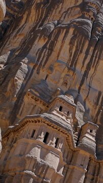 Tourists exploring the impressive rock cut nabataean tombs and monumental facades carved into the sandstone cliffs at the archaeological site of hegra, al ula, saudi arabia