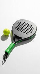 Modern black and green padel tennis racket with a yellow ball on a clean white background, ready for play.