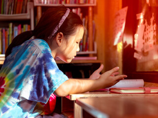 Young girl concentrating on homework at wooden desk
