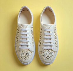 Pair of white perforated leather sneakers on a yellow background