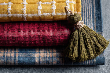 Closeup of a stack of textured fabrics with a decorative tassel