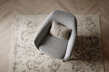 Cozy armchair with textured pillow on a patterned rug, topdown view