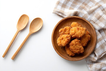 Crispy chicken nuggets in a wooden bowl with spoons isolated on white background