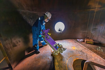 Male worker inspection floor scan tank oil of rust wall, loss of thickness bottom plate in the manhole tank to work inside
