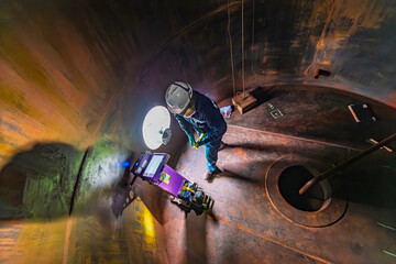 Male worker inspection floor scan tank oil of rust wall, loss of thickness bottom plate in the manhole tank to work inside