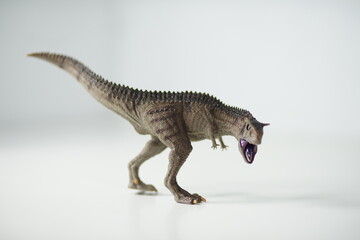 A carnotaurus figure with intricate skin texture poses menacingly on a plain