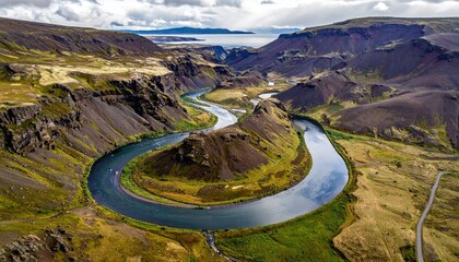 Aerial View of Winding River Through Rocky Terrain with Mountain Backdrop Under Cloudy Blue Sky on Sunny Day Landscape