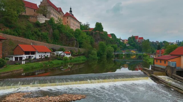 An aerial or panoramic view of the charming spa town of Bechyně in the South Bohemian Region of the Czech Republic, showcasing its historic castle overlooking the scenic Lužnice River with a weir, tra