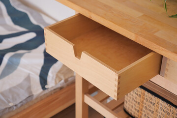 Wooden desk with open drawer in a cozy bedroom setting