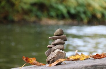 Balancepyramide am Fluss im Herbst mit Laub als Symbol für Ruhe und Entspannung