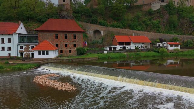 Aerial footage capturing the picturesque town of Bechyně in the Czech Republic, showcasing its historic architecture, the tranquil Lužnice River, and a scenic weir. The shot highlights the charming bl