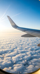 Fototapeta premium Inspirational aerial view from a passenger jet window showing the wing soaring over a beautiful cloudscape towards a brilliant sun