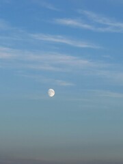 Soft evening sky with a bright half moon rising above the horizon on a peaceful twilight night.