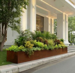 A rectangular planter overflowing with lush greenery in front of a building's white facade